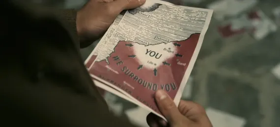 Screenshot from "Dunkirk" showing soldier holding leaflet saying "we surround you"