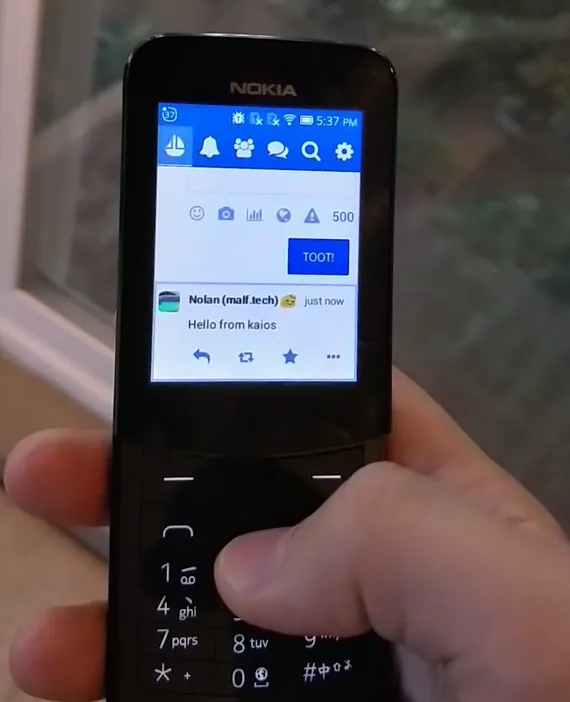Photo of my hand holding a Nokia 8110 4G running Pinafore on KaiOS