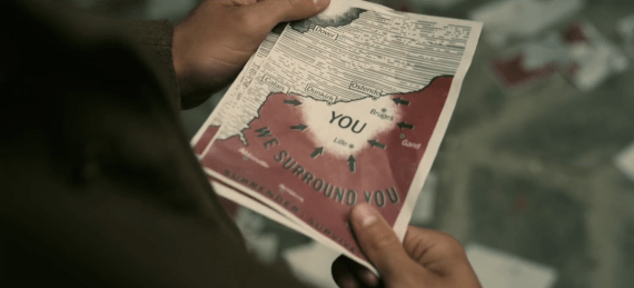 Screenshot from "Dunkirk" showing soldier holding leaflet saying "we surround you"