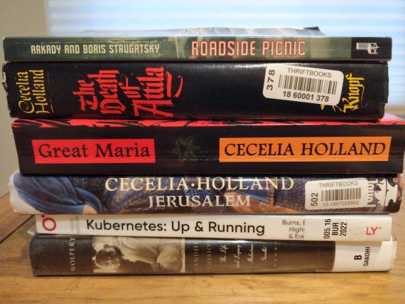 A stack of books on a shelf, most of which are mentioned in this post